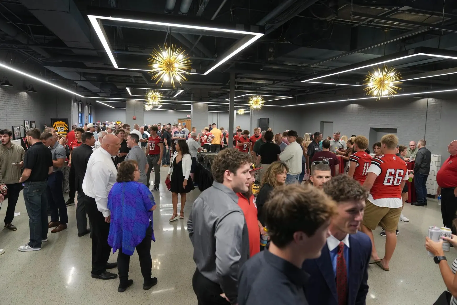 A packed reception in the Event Center at Wadsworth Square, under the sputnik chandeliers