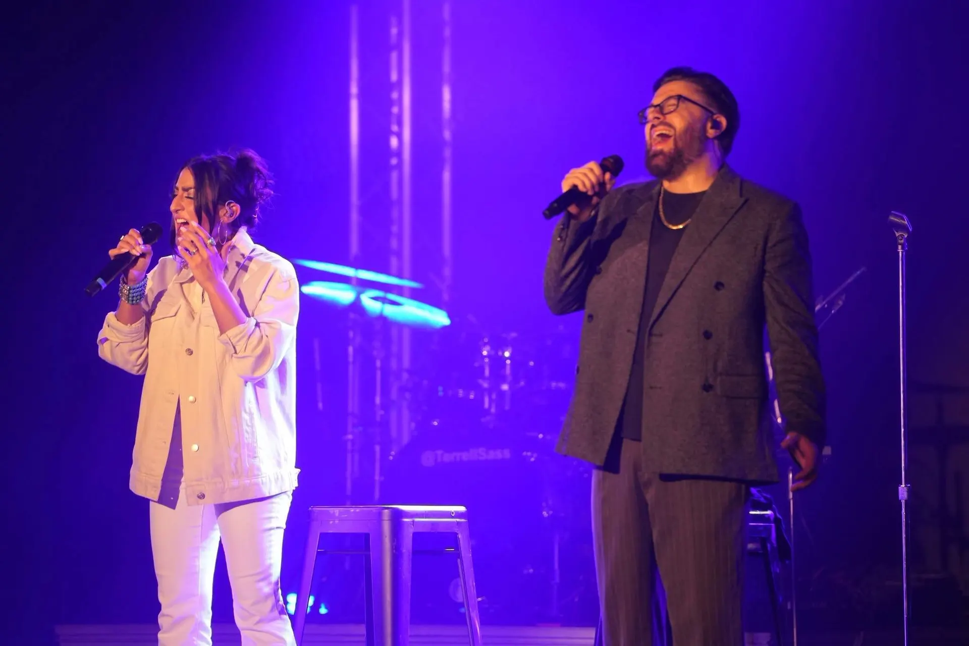 Two vocalists singing under purple light