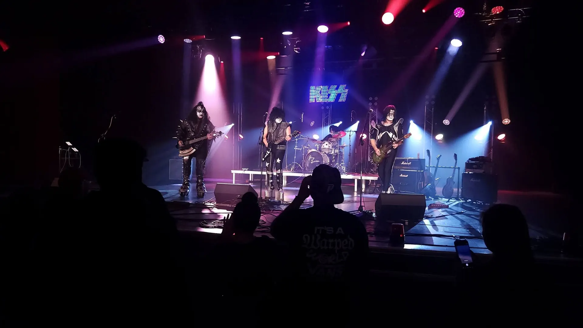 A KISS tribute band on stage, photographed from the front rows